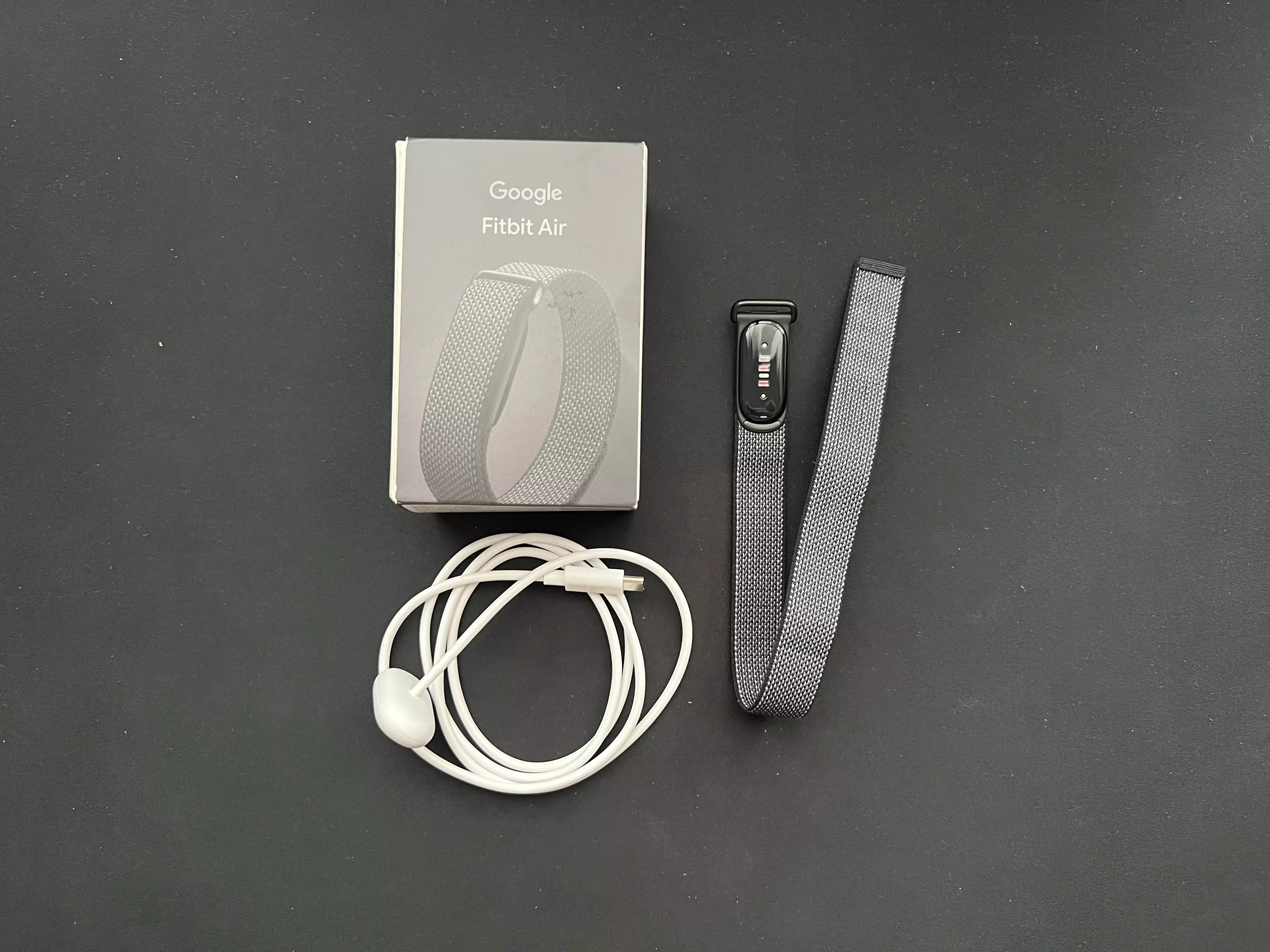 Contenu de la boîte du Google Fitbit Air avec tracker noir et câble de charge