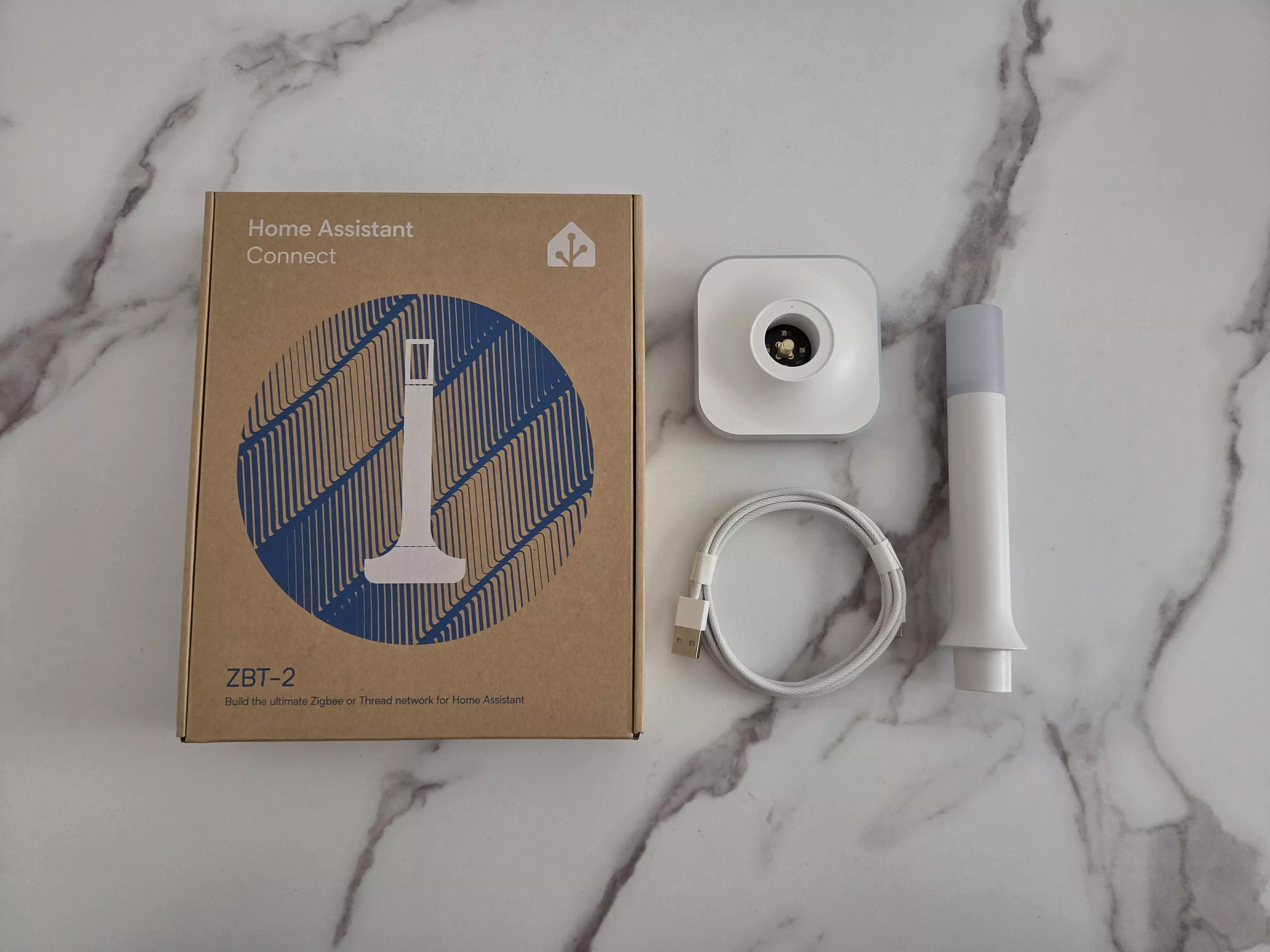 Home Assistant Connect ZBT-2 avec sa boîte, sa base carrée, son antenne et son câble USB tressé