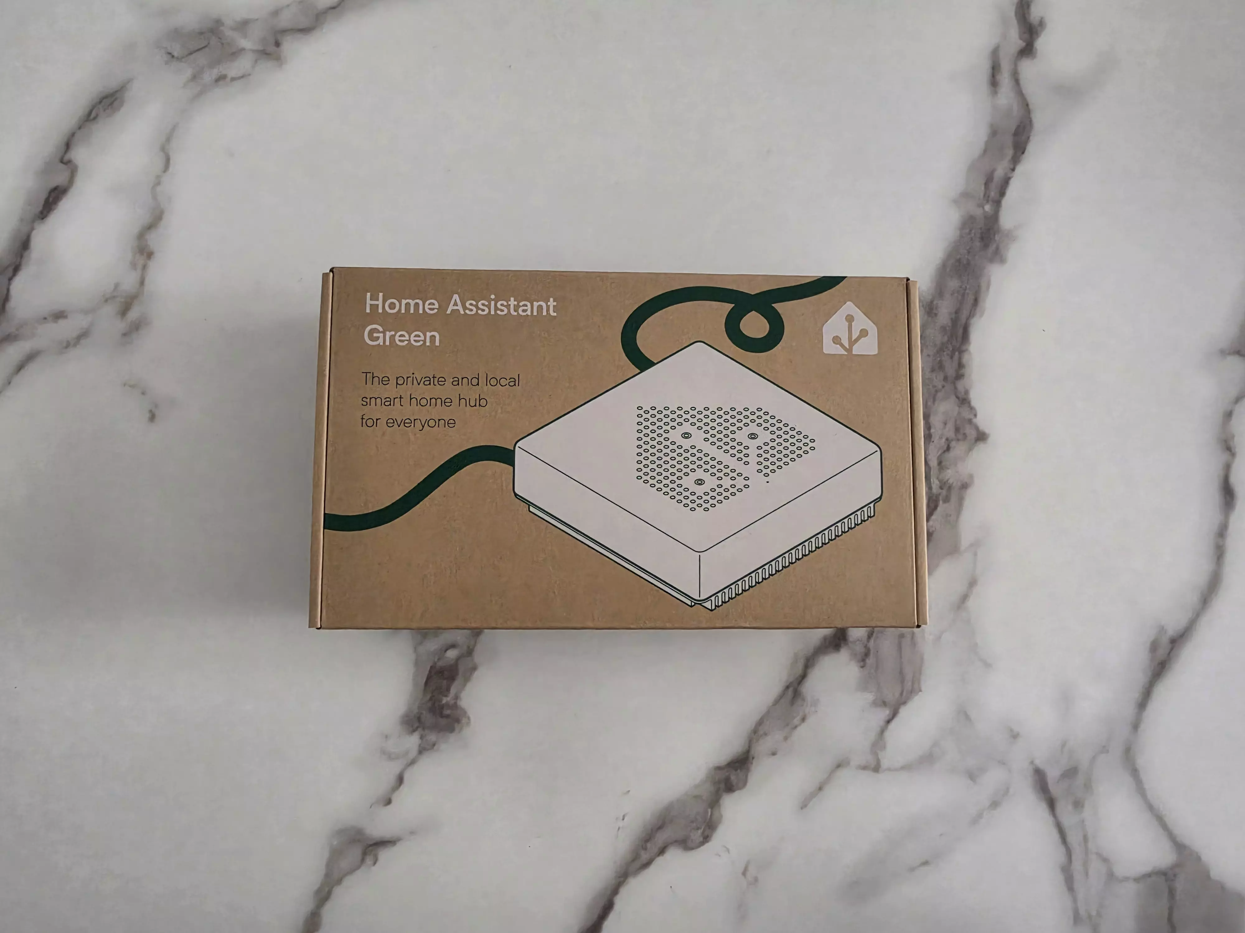 Boîte en carton du Home Assistant Green avec le dessin du boîtier blanc