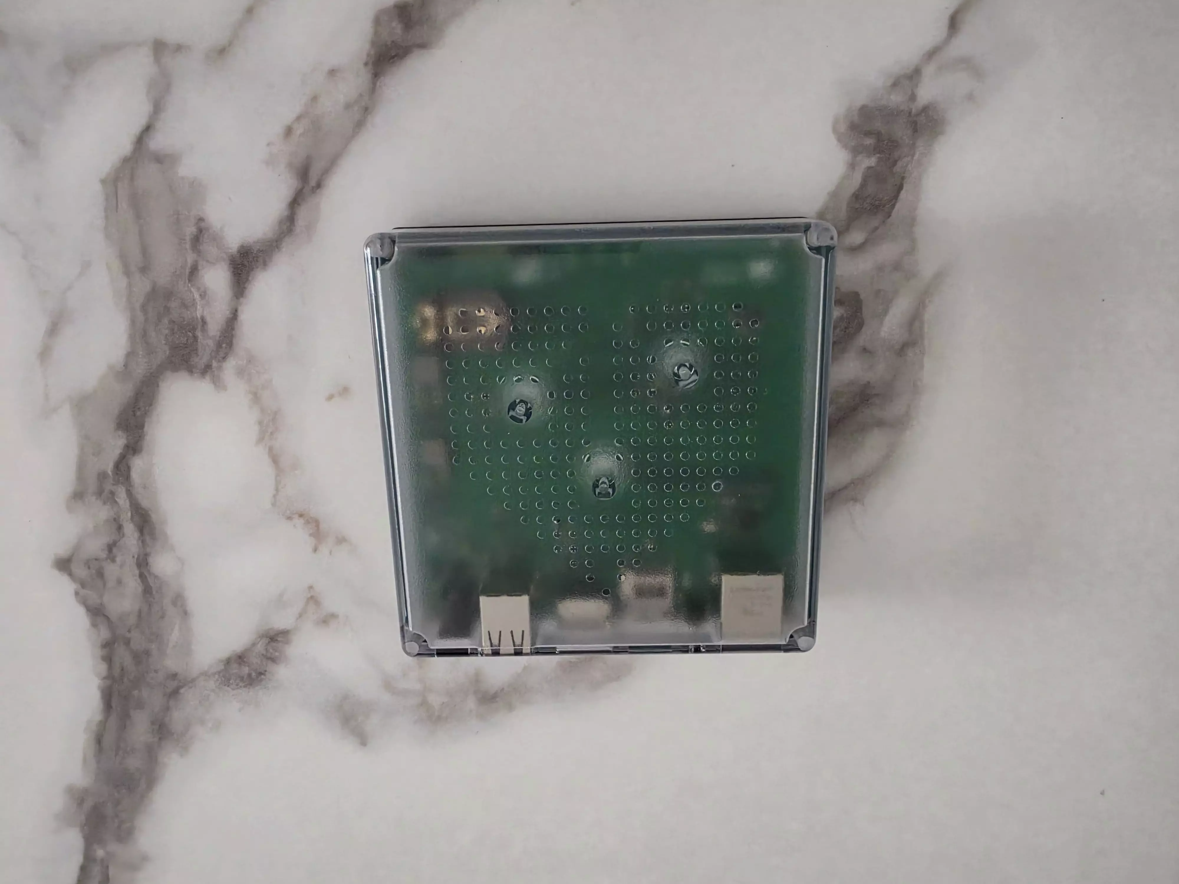 Home Assistant Green vu de dessus à travers son boîtier translucide laissant apparaître la carte électronique
