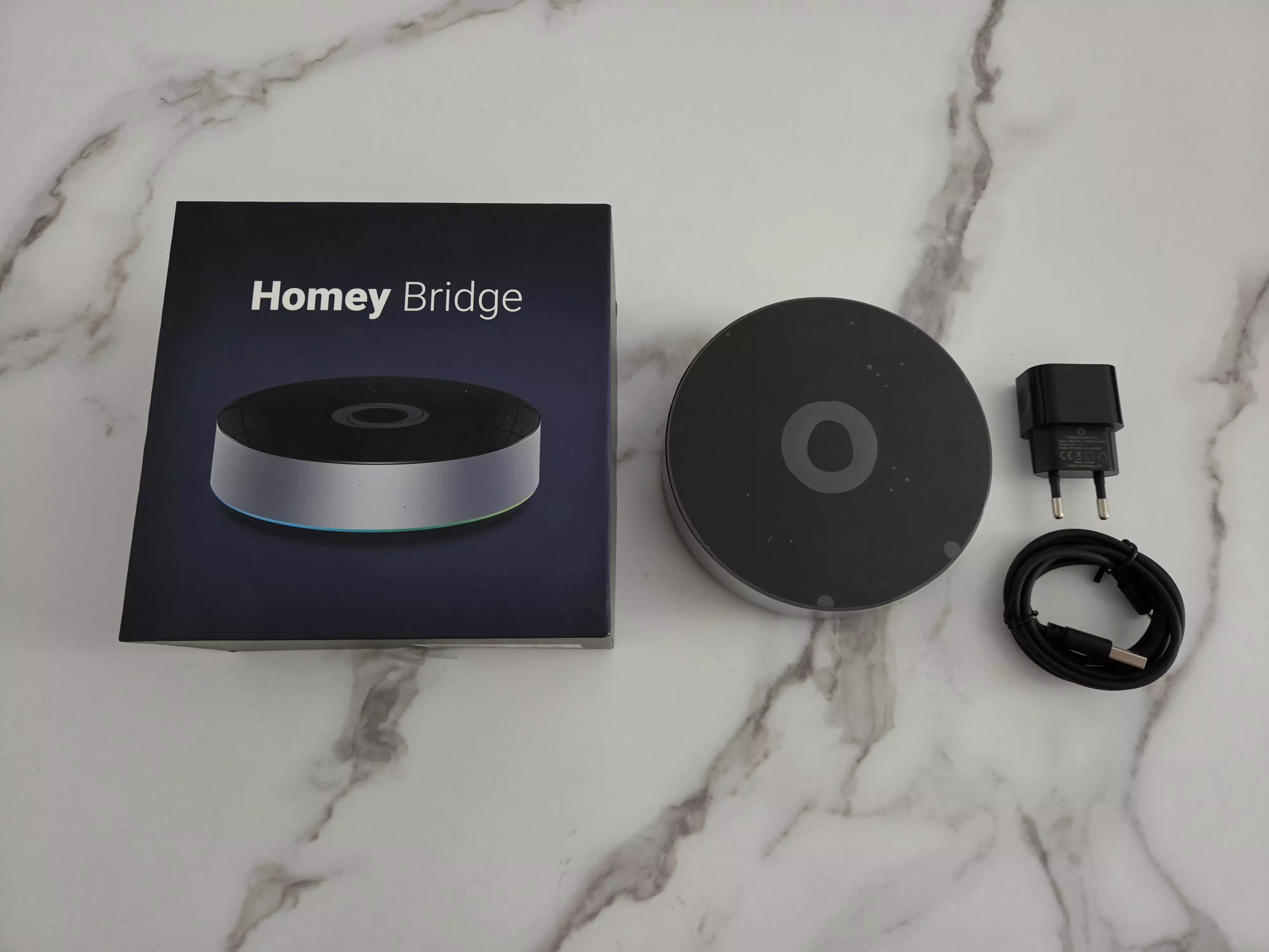 Homey Bridge avec sa boîte, son adaptateur secteur et son câble d’alimentation