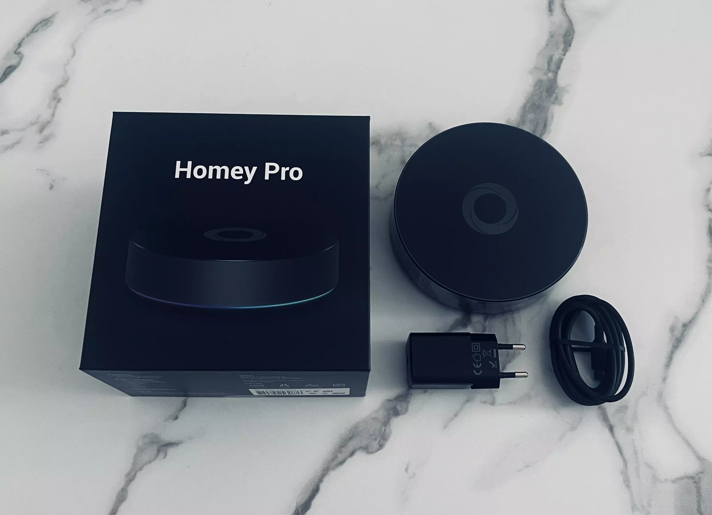 Homey Pro avec sa boîte, son adaptateur secteur et son câble USB-C