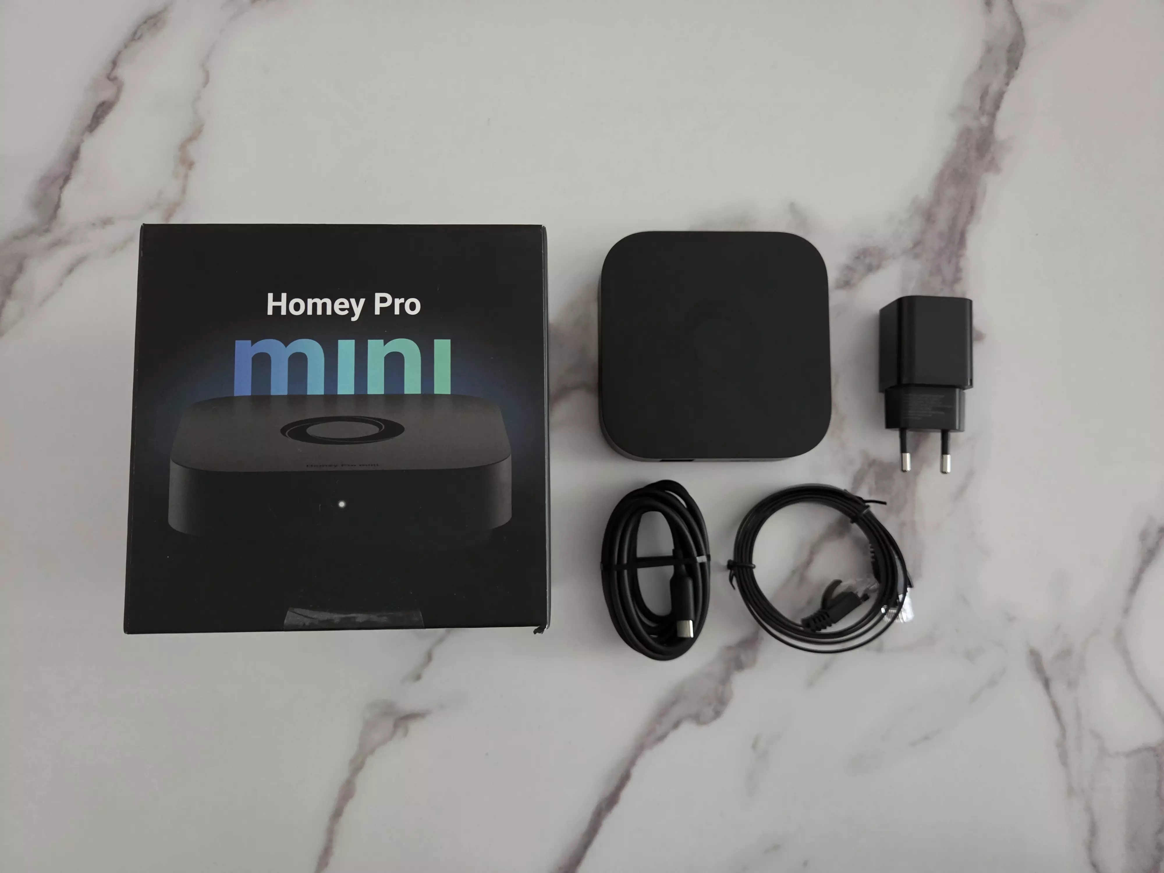 Homey Pro mini avec sa boîte, son alimentation, son câble USB-C et son câble Ethernet