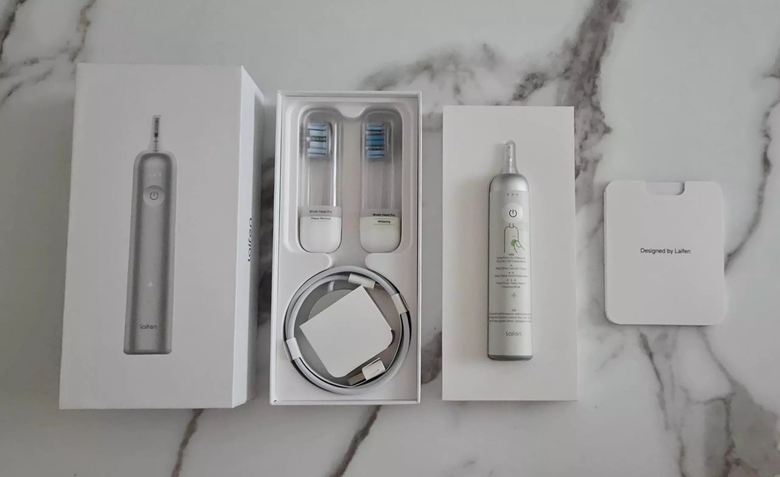 Contenu de la boîte de la Laifen Wave Pro avec deux têtes, chargeur sans fil, câble et documentation