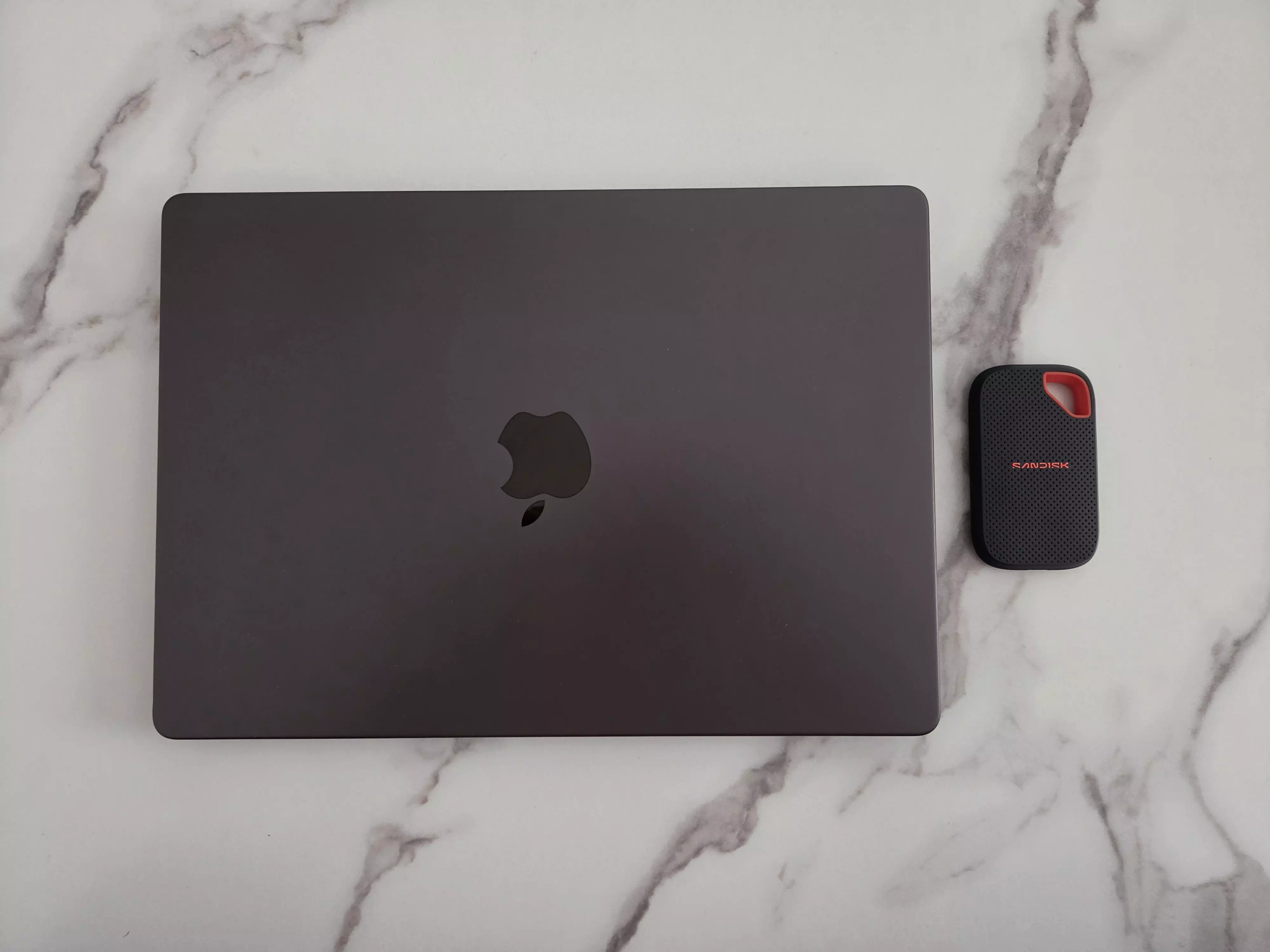 SANDISK Extreme Portable SSD V3 2 To posé à côté d’un MacBook Pro fermé