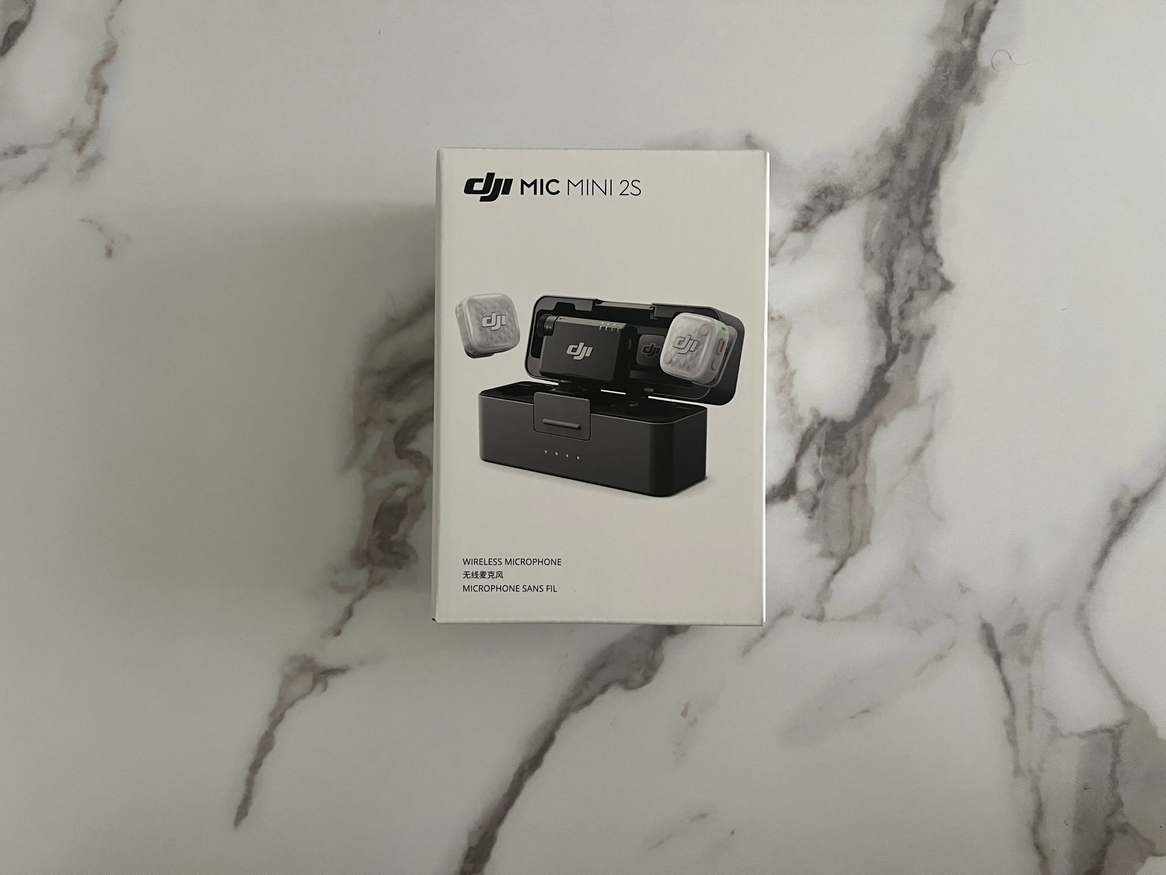 Boîte blanche du DJI Mic Mini 2S kit 2 TX posée seule sur une surface marbrée