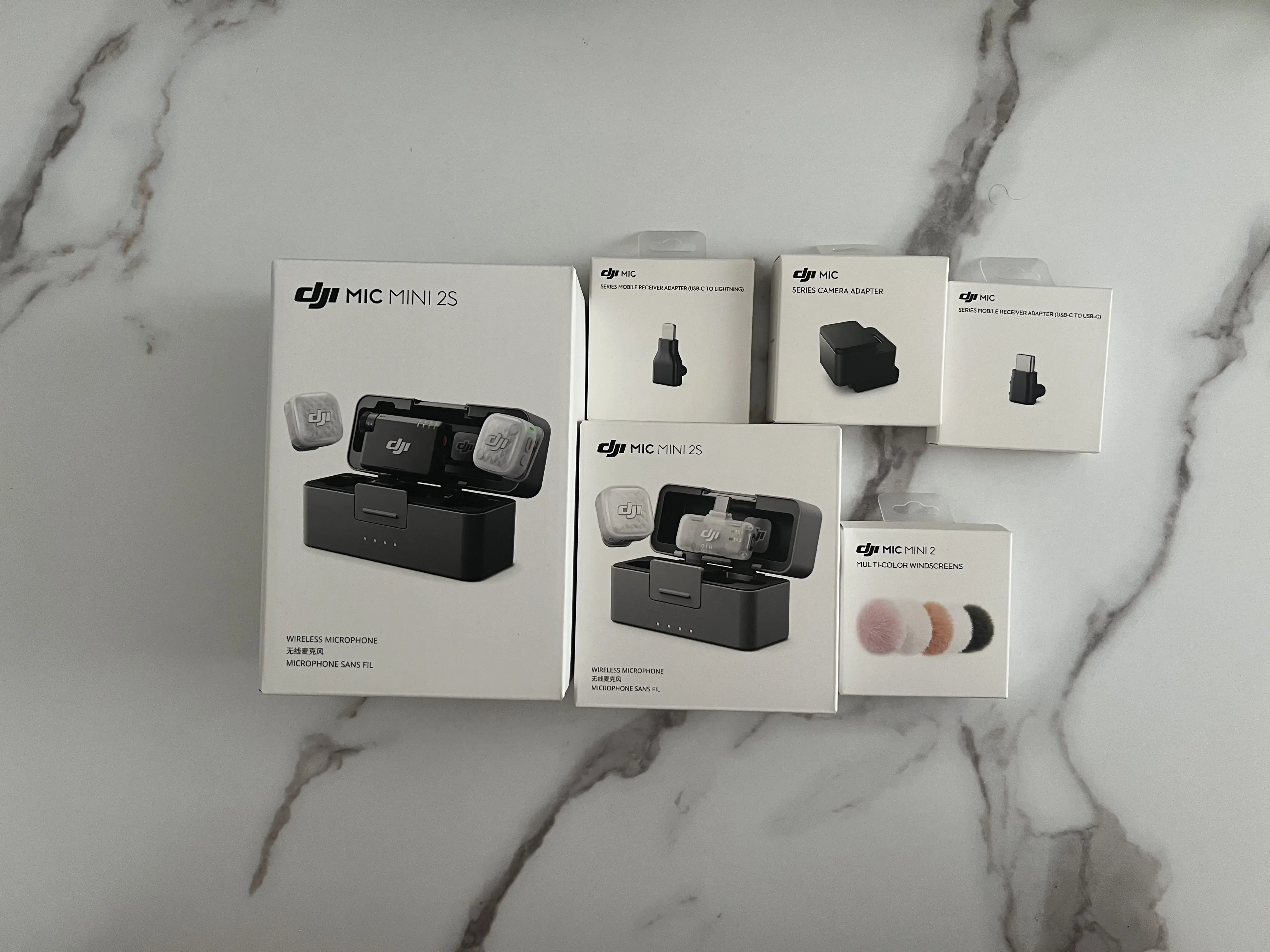 Boîtes du DJI Mic Mini 2S avec adaptateurs Lightning, USB-C, caméra et bonnettes multicolores