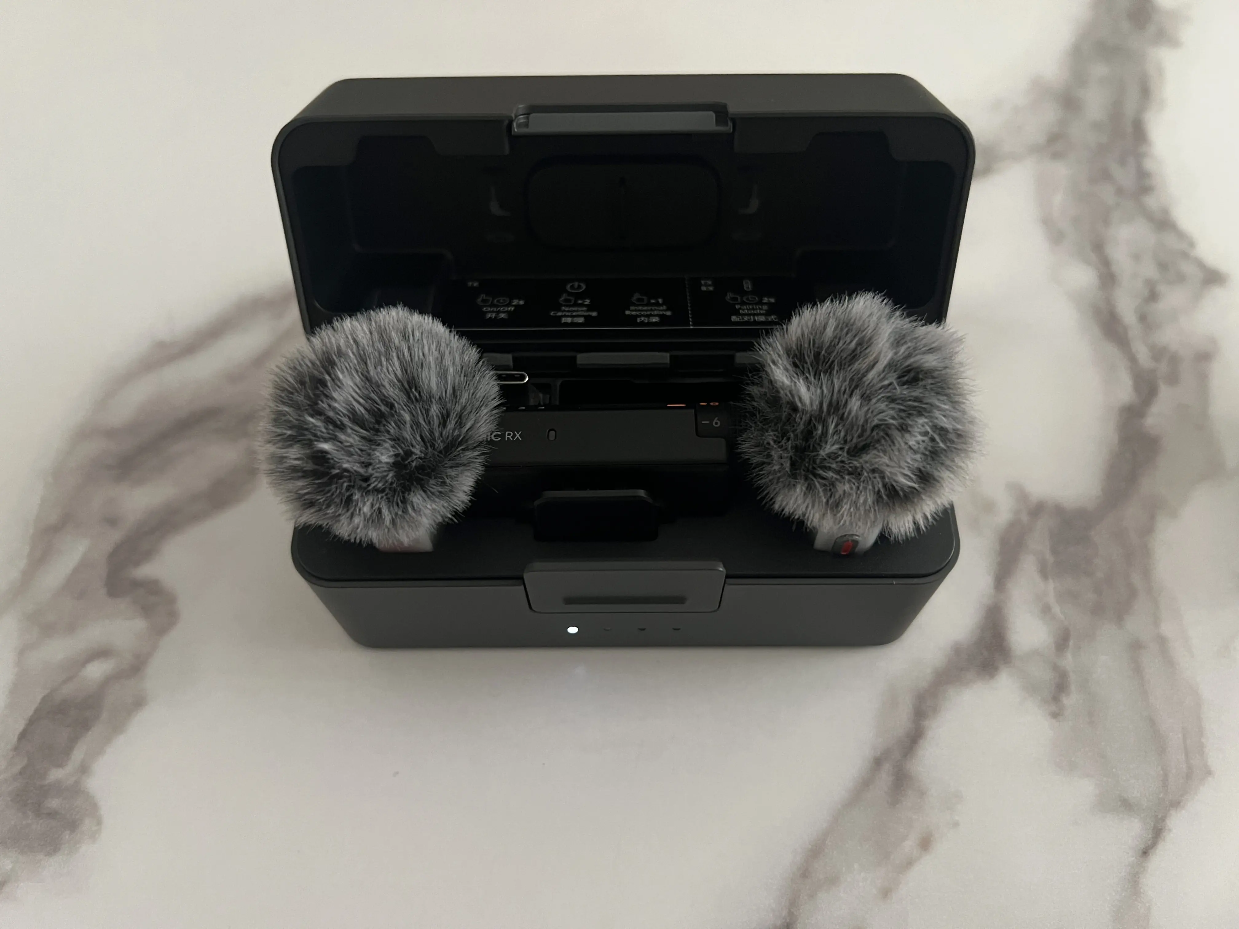 Boîtier de recharge DJI Mic Mini 2S ouvert avec deux émetteurs équipés de bonnettes