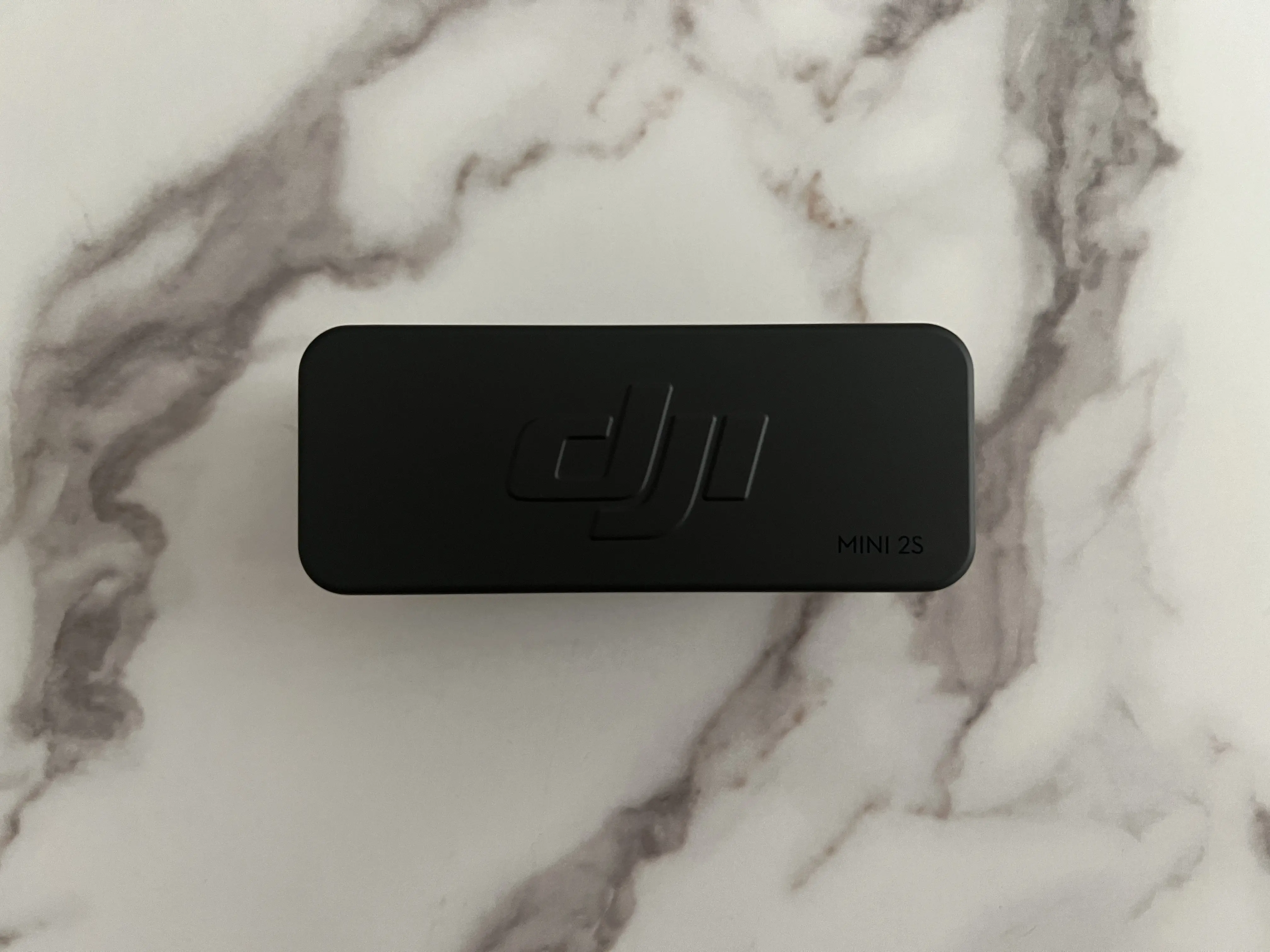 Boîtier de recharge noir du DJI Mic Mini 2S fermé avec logo DJI et inscription Mini 2S