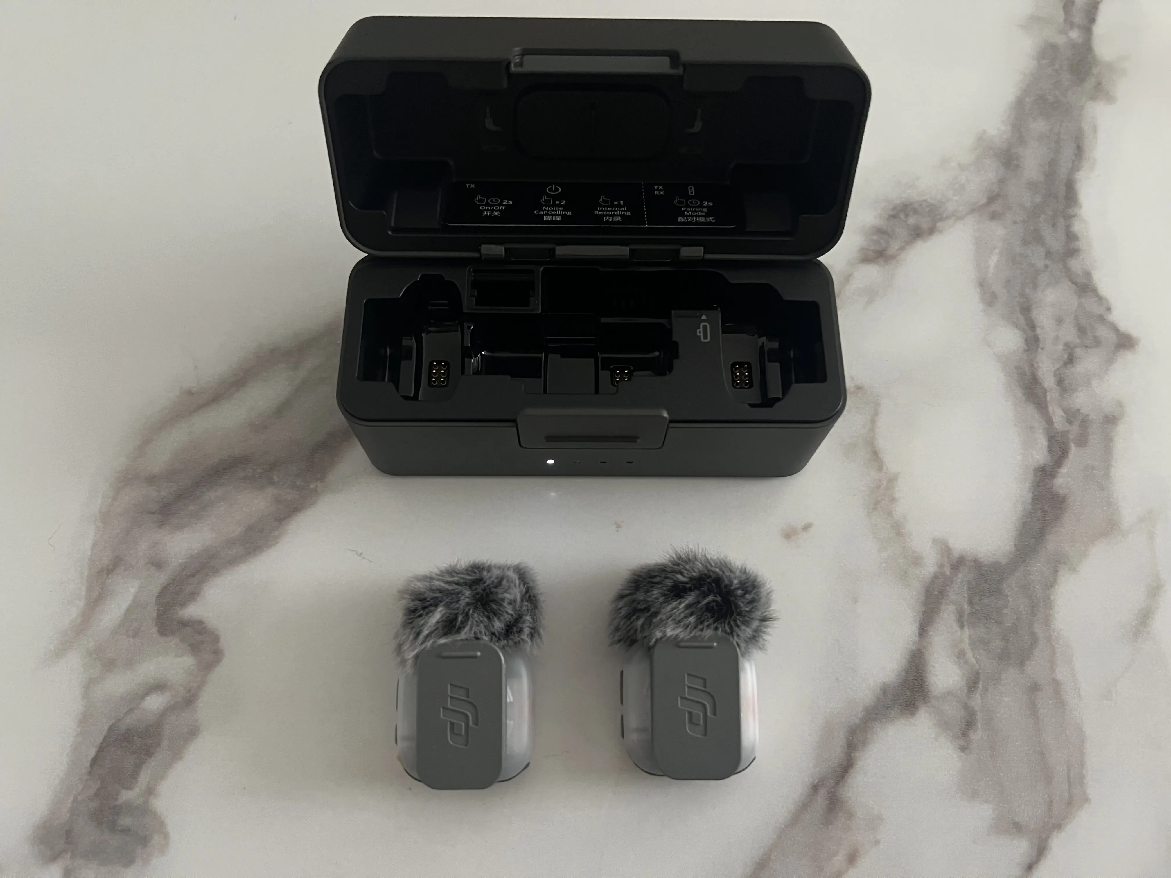 Deux émetteurs DJI Mic Mini 2S vus de dos avec leurs clips magnétiques devant le boîtier ouvert