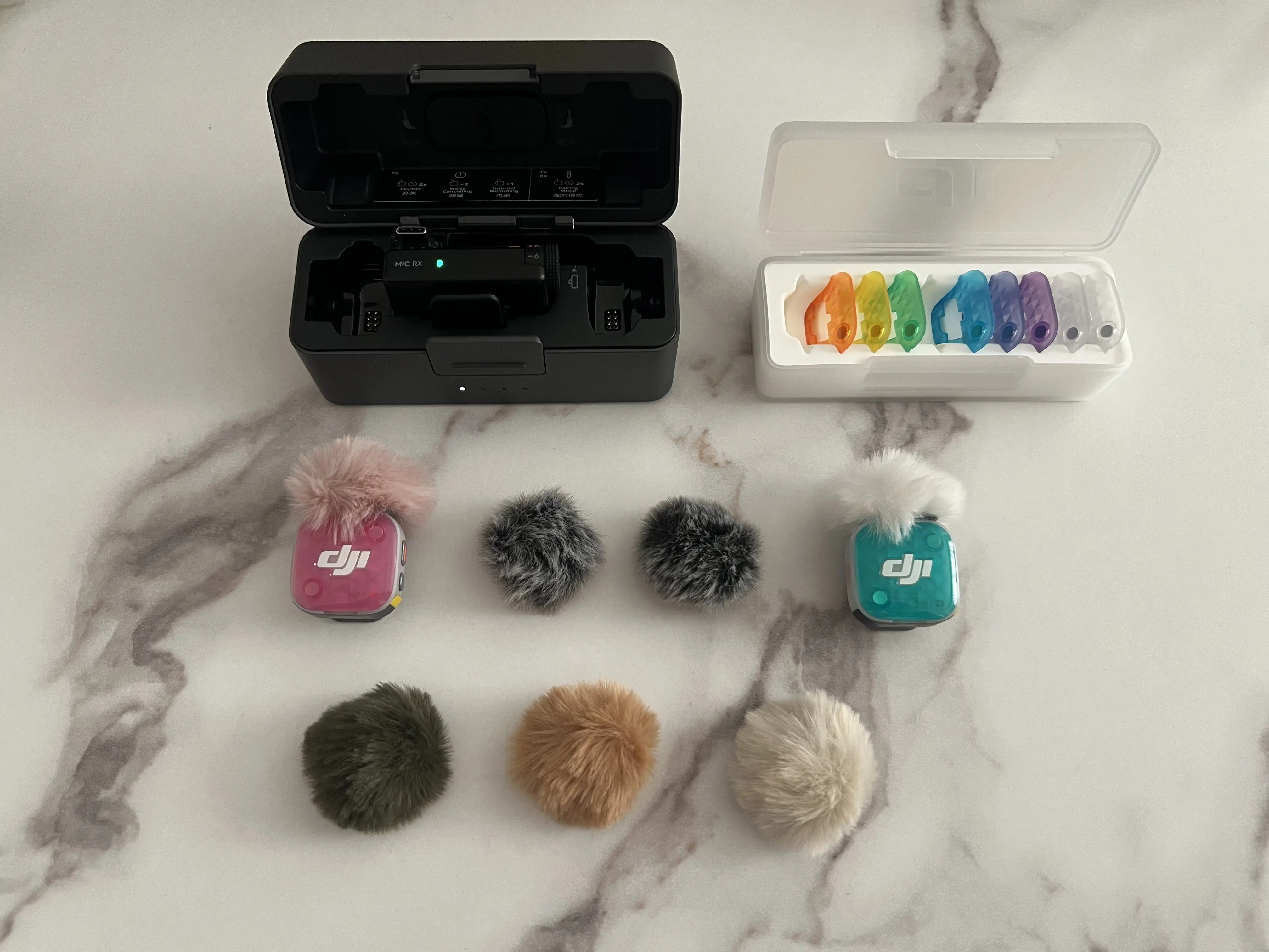 DJI Mic Mini 2S avec deux émetteurs colorés, plusieurs coques magnétiques et différentes bonnettes anti-vent