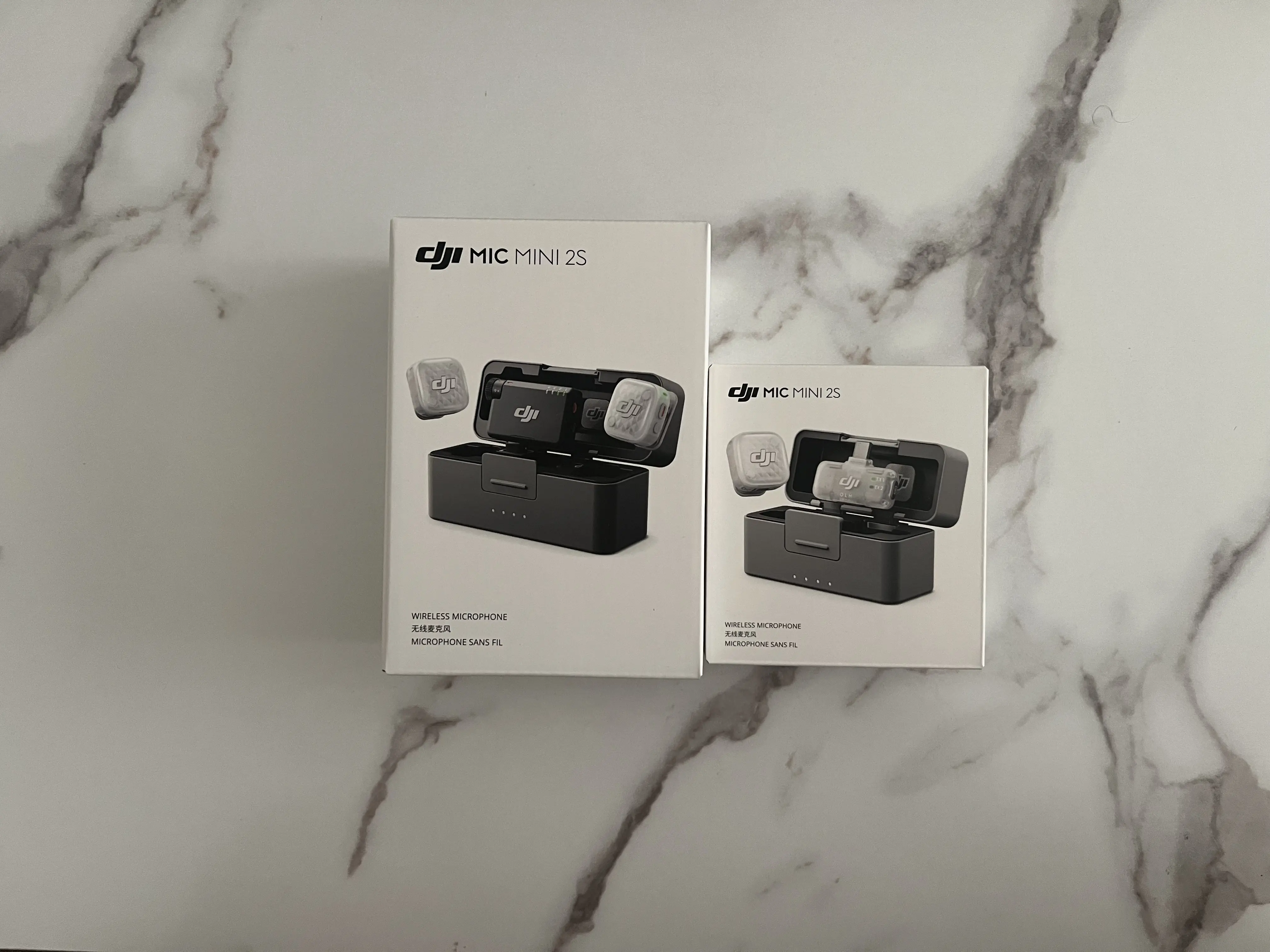Emballages des deux formats du DJI Mic Mini 2S présentés ensemble sur une surface marbrée