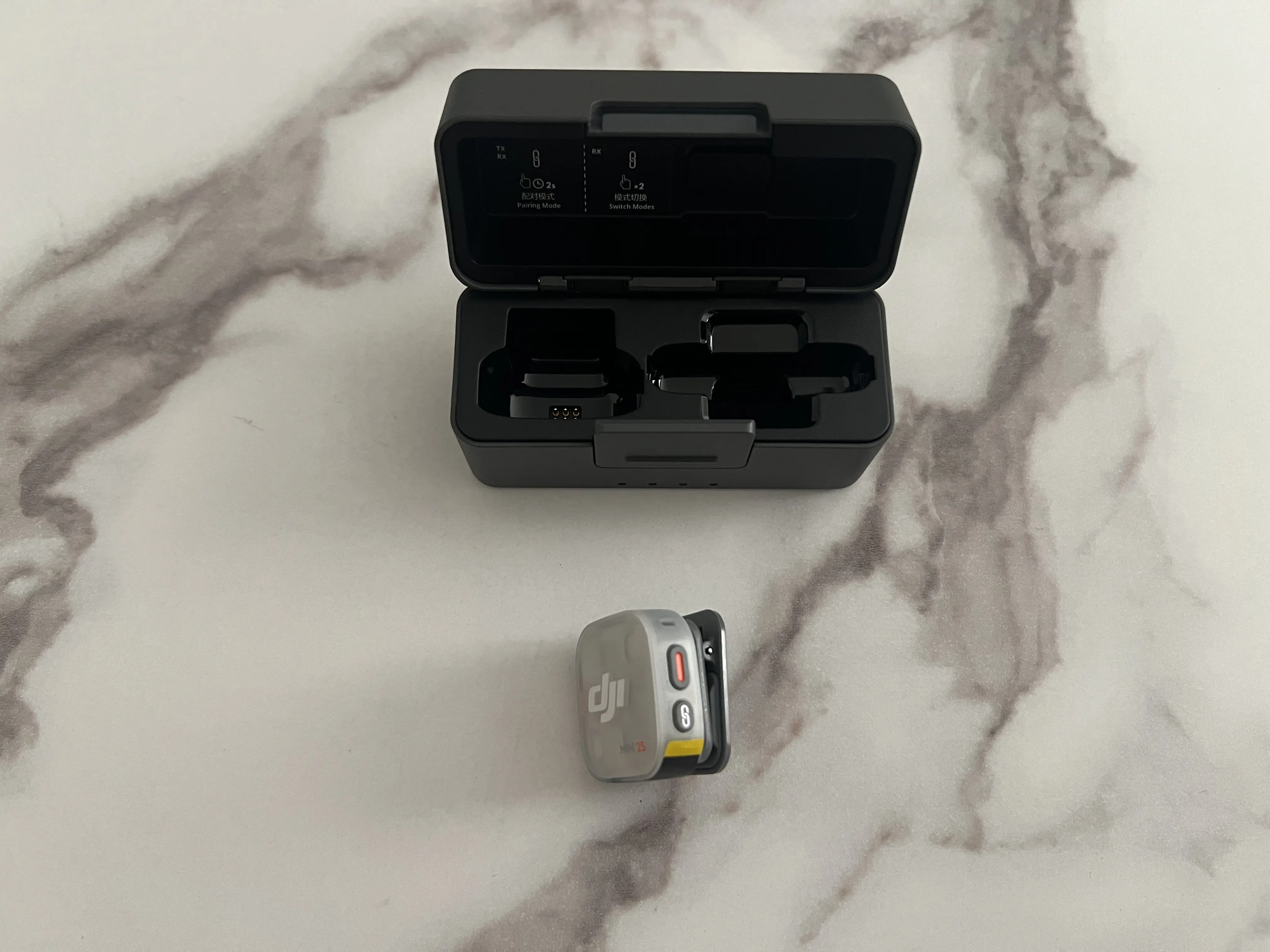 DJI Mic Mini 2S vu de côté avec bouton d’enregistrement, bouton d’appairage et repère jaune