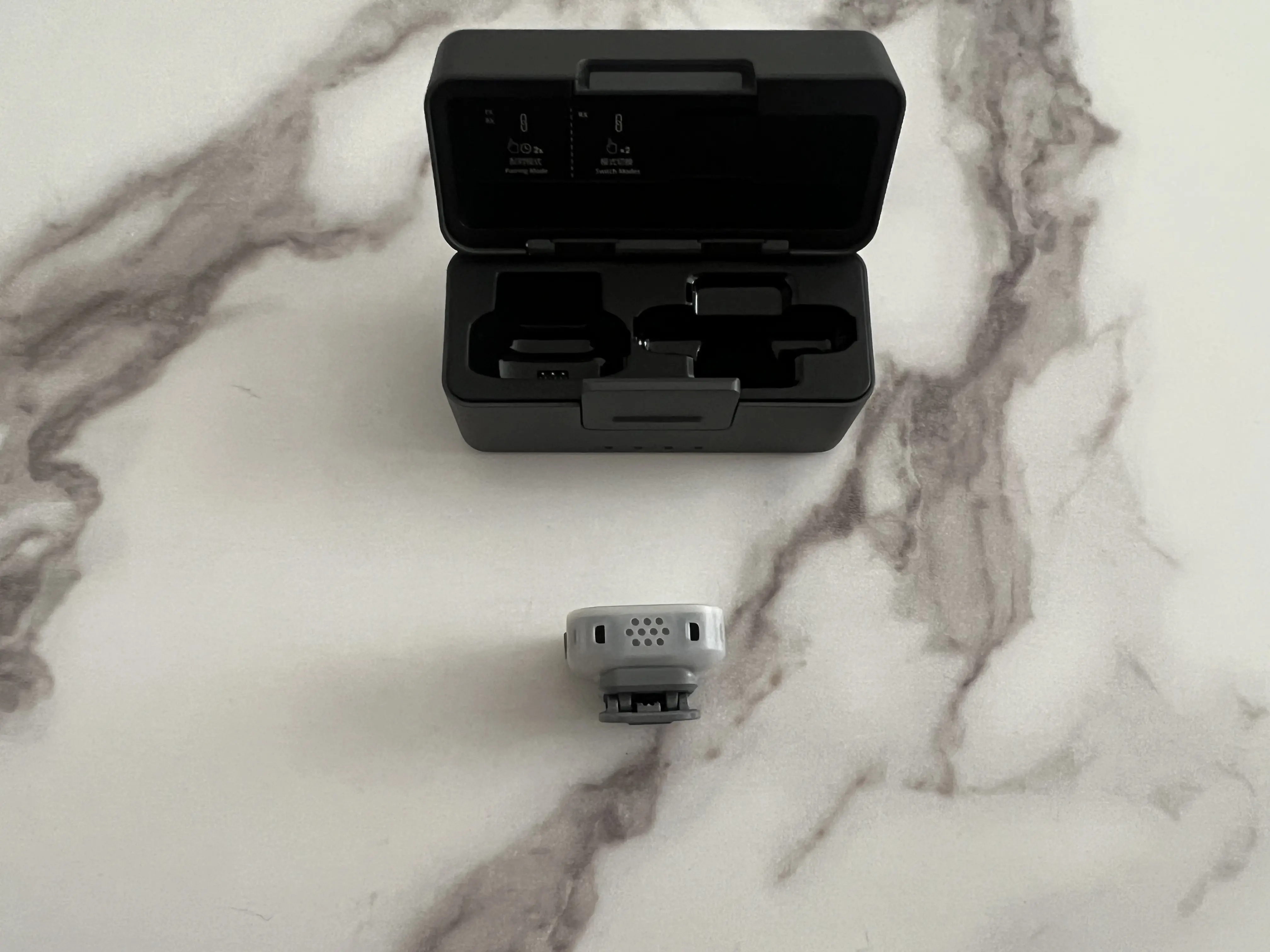 Émetteur DJI Mic Mini 2S vu par dessous avec grille du microphone et clip