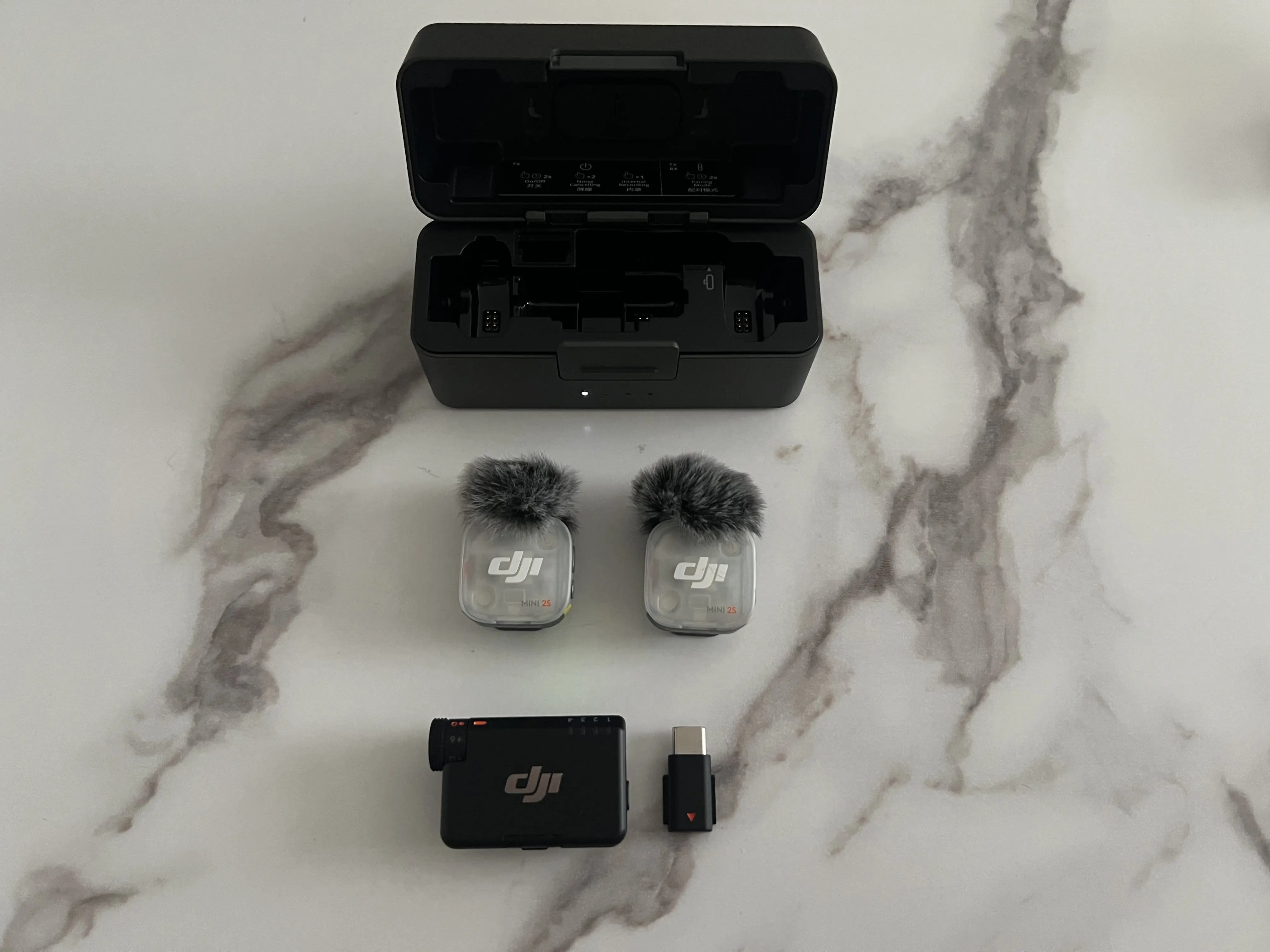 Deux émetteurs DJI Mic Mini 2S, récepteur principal, adaptateur USB-C et boîtier de recharge ouvert
