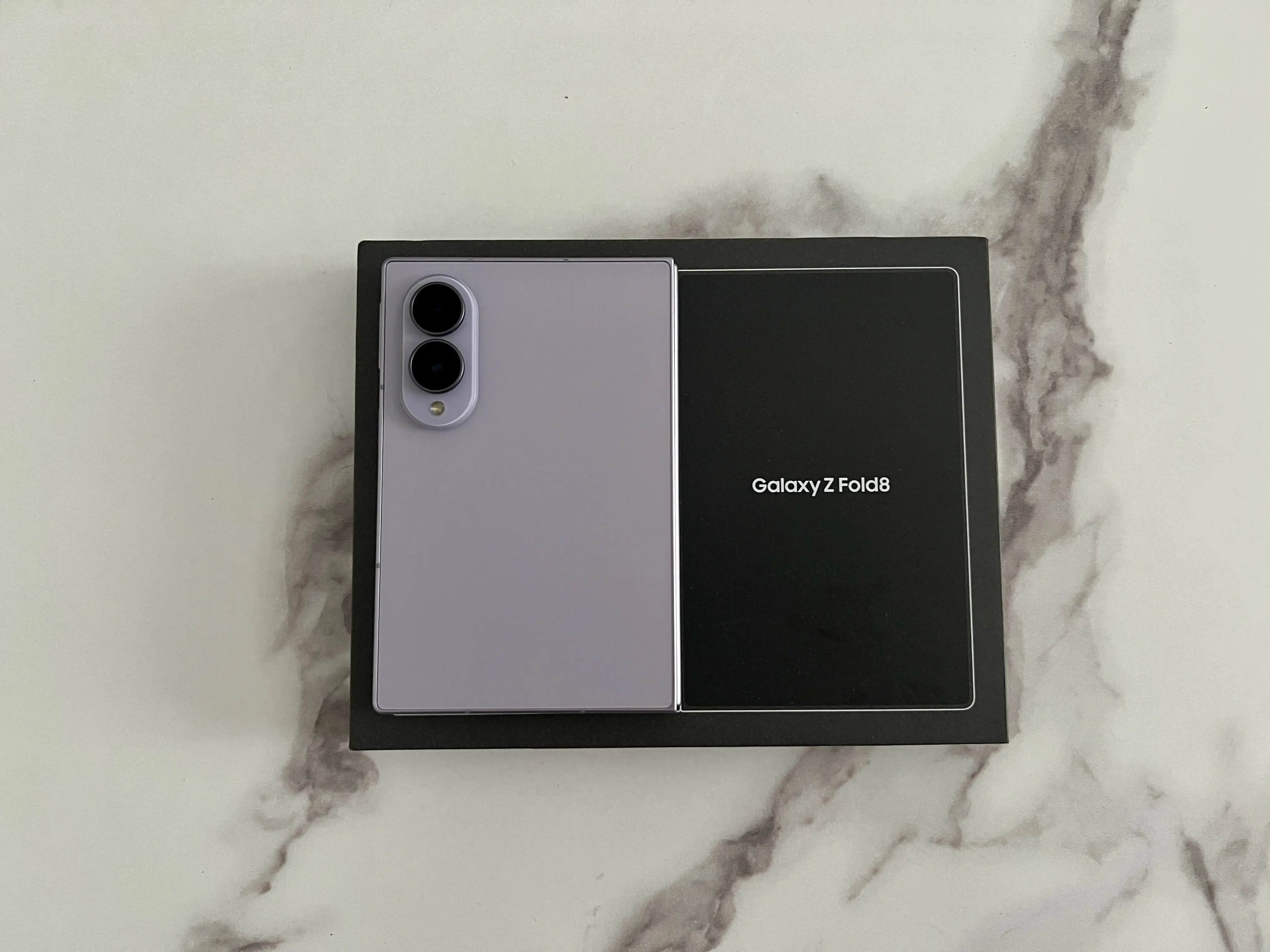 Samsung Galaxy Z Fold8 Lavande fermé posé sur sa boîte noire