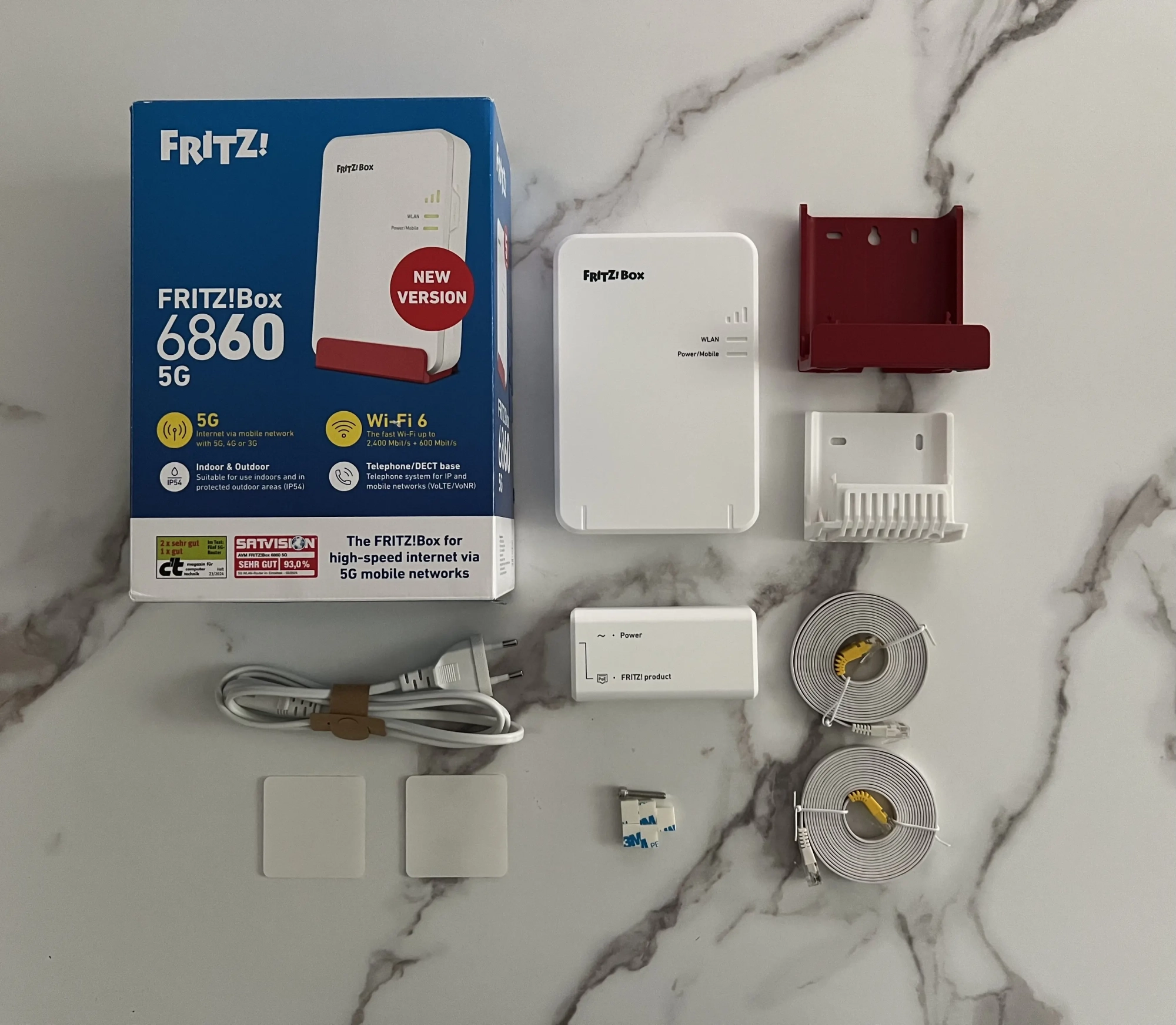 Contenu de la boîte FRITZ!Box 6860 5G avec supports, injecteur PoE et câbles Ethernet