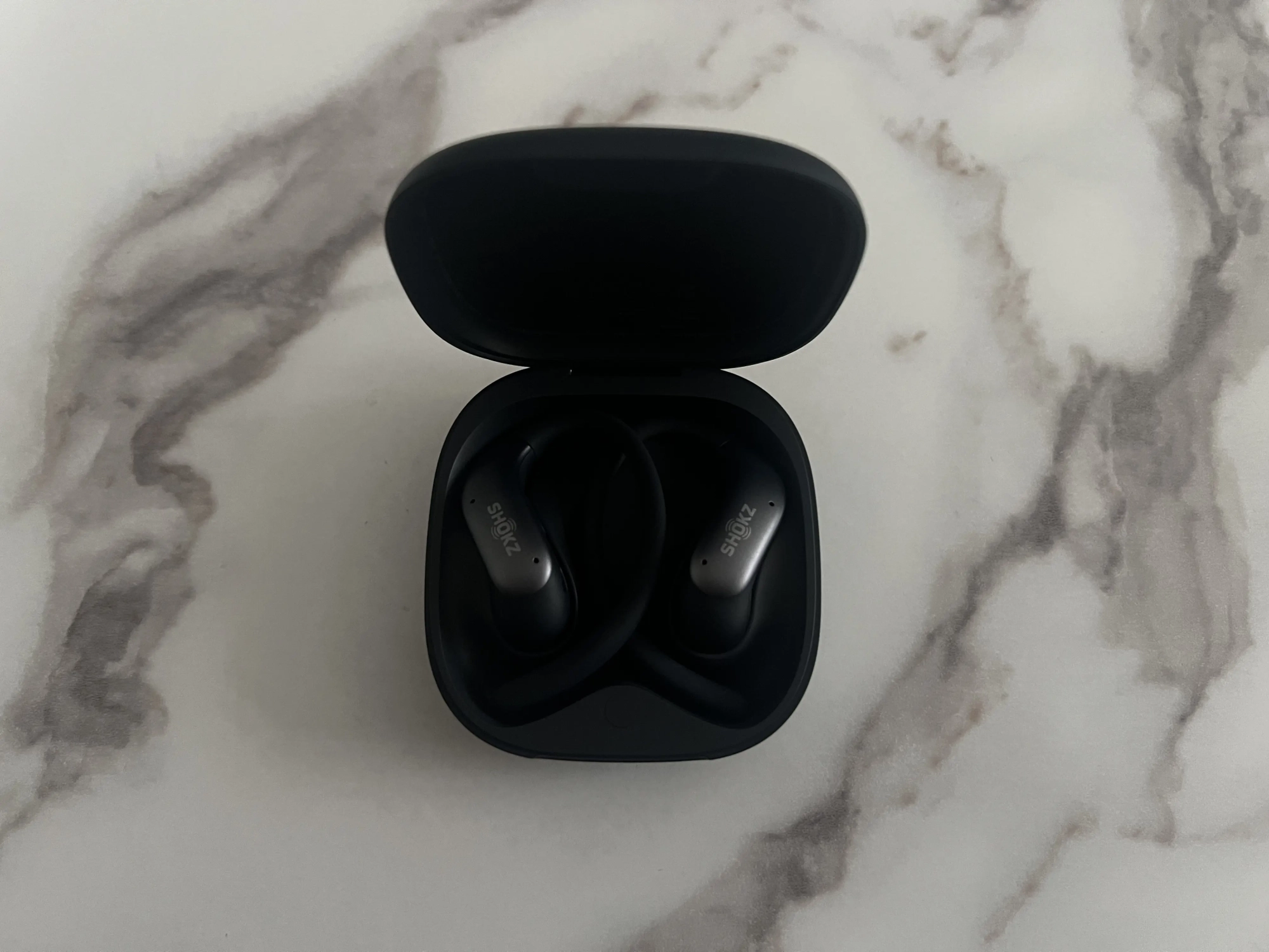Deux écouteurs Shokz OpenFit Air 2 rangés dans leur boîtier de recharge ouvert